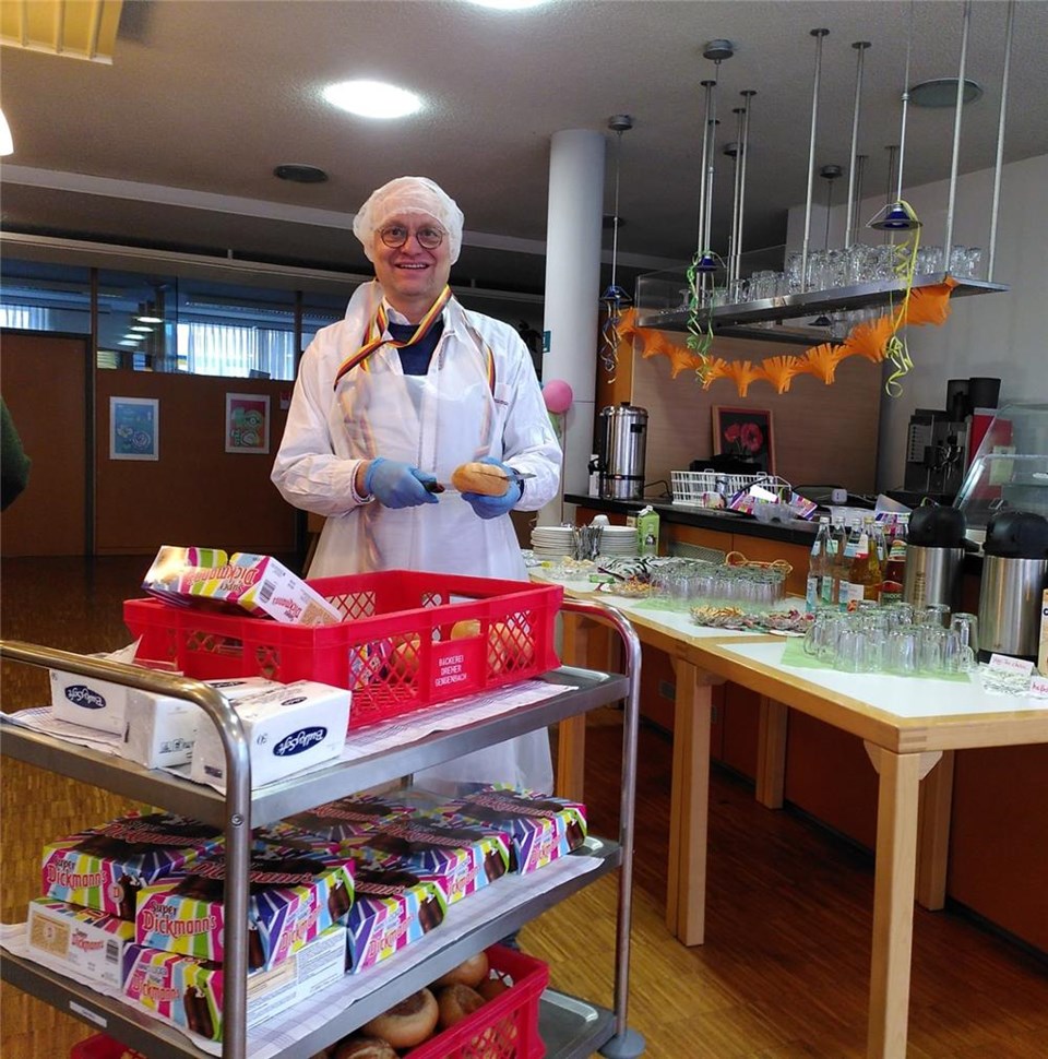 Rainer Leweling mit einem Servierwagen voller Brötchen und Schokoküsse.