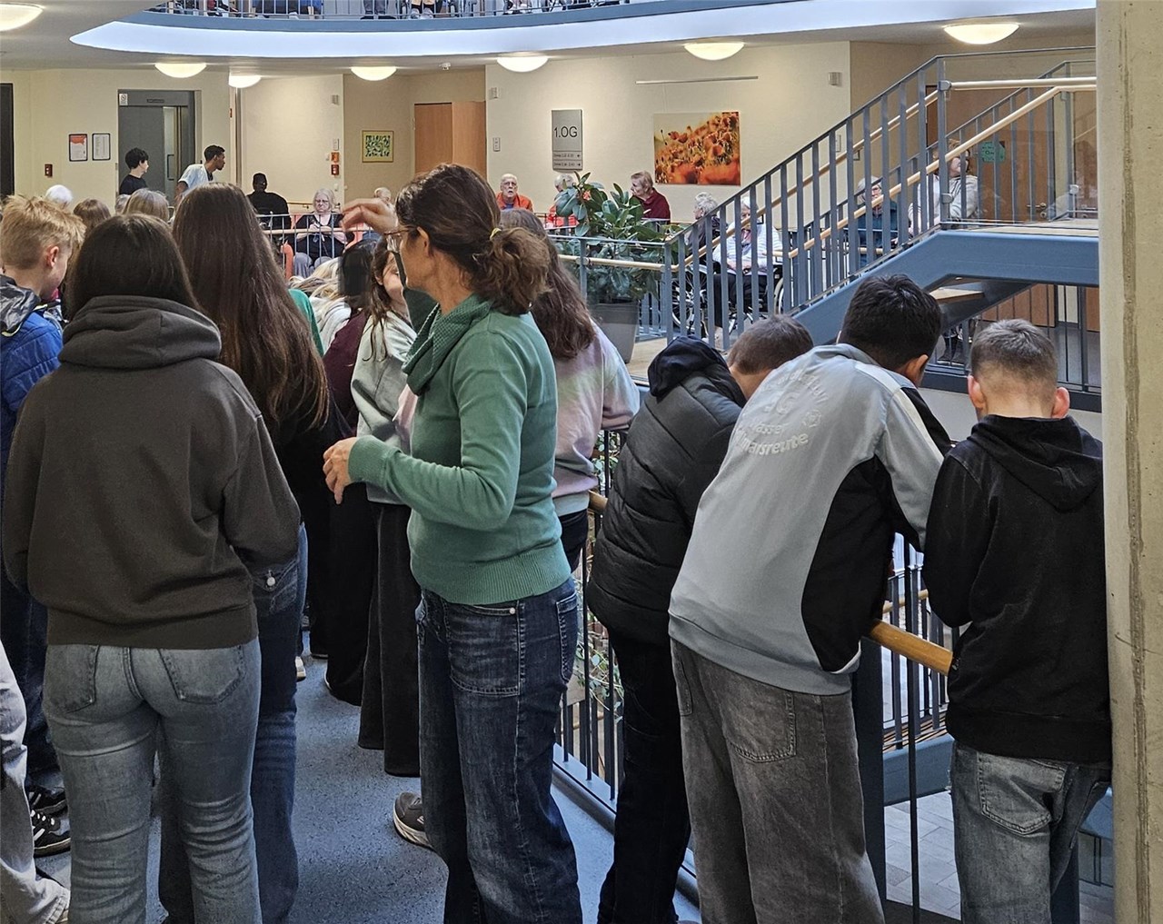 Eine Gruppe von jungen und Bewohner*innen steht bzw. sitzt im Foyer.