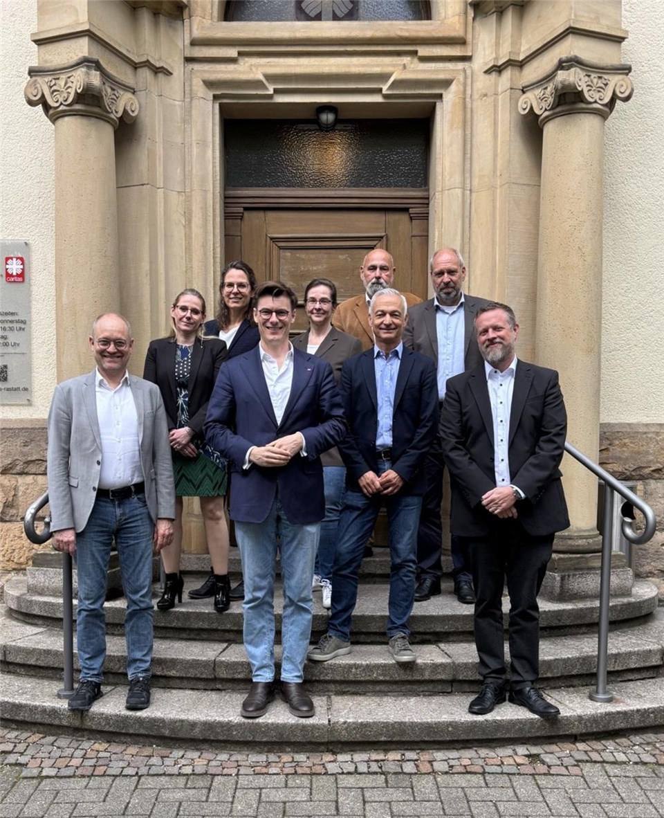 Acht Mitglieder der Diözesanarbeitsgemeinschaft Arbeit stehen mit Kai Whittaker (MdB) für ein Gruppenfoto auf einer Treppe.