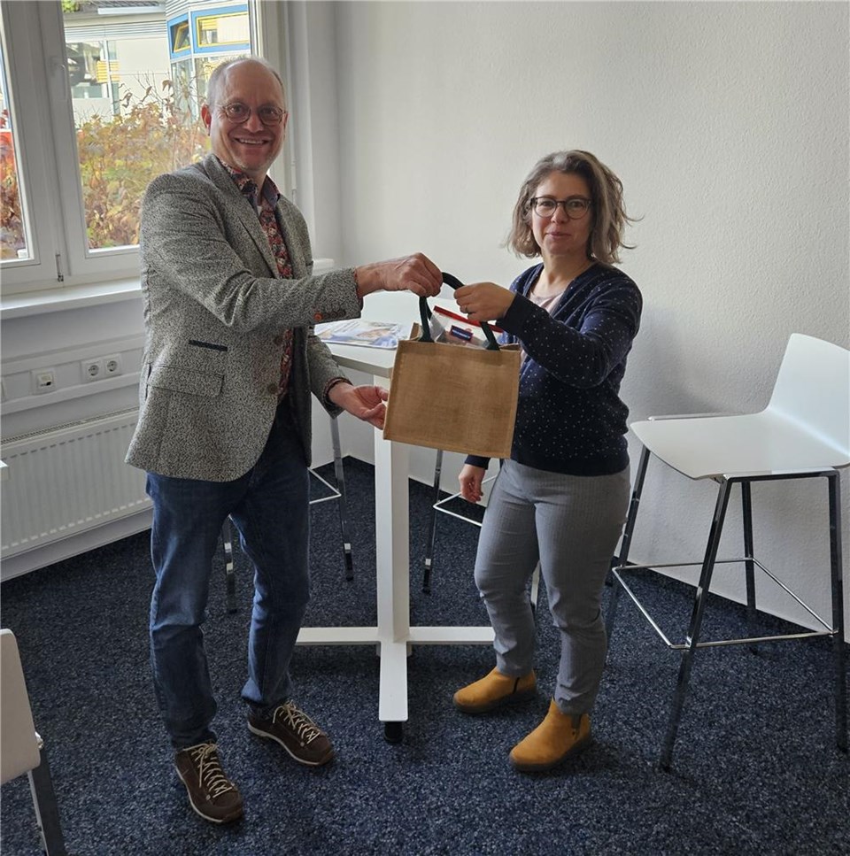 Das Bild zeigt Vorstand Rainer Leweling, links, der Anne Schirmer ein Begrüßungsgeschenk überreicht