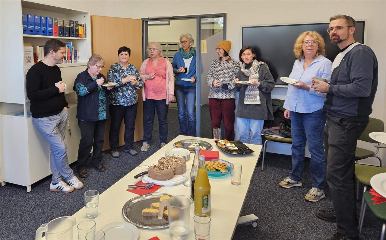 Das Foto zeigt Reinhilde Zängle (3. Von links) im Kreise der Kolleginnen und Kollegen. Im Vordergrund der gedeckte Tisch mit Torte in der Mitte.