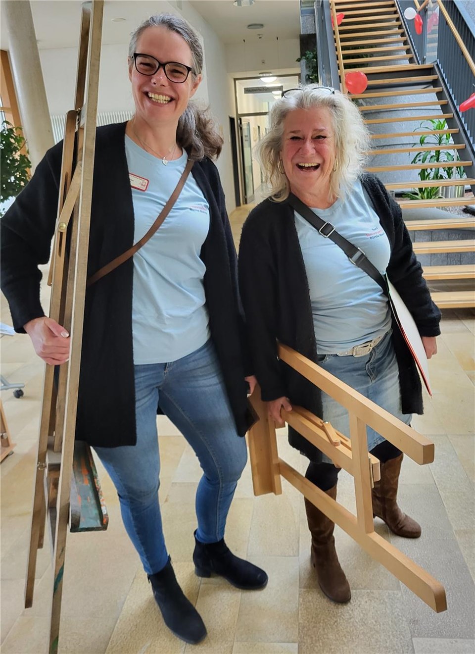 Das Foto zeigt die beiden Kunsttherapeutinnen mit Staffeleien in der Hand im Foyer des Seniorenzentrums Bürkle-Bleiche. 