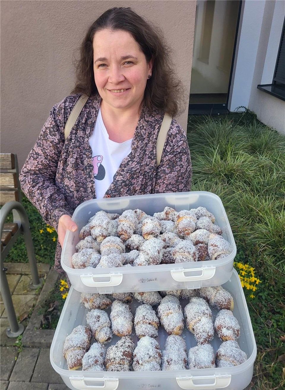 Olga Moglidea schaut in die Kamera und hat zwei großen Schalen Gebäck in der Hand