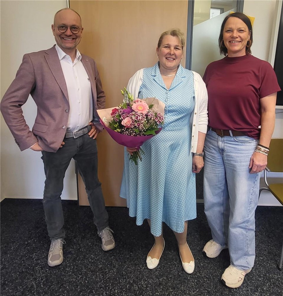 Rainer Leweling, Stephanie Engels und Katja Rambach stehen nebeneinander und schauen in die Kamera, Stephanie Engels hat einen Blumenstrauß in der Hand.
