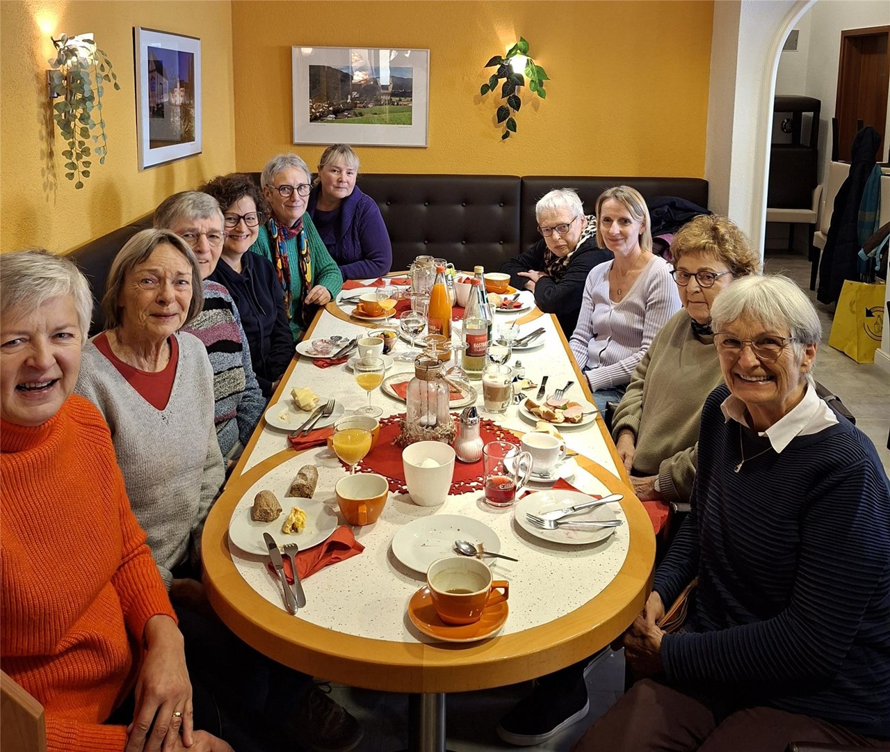 Das Bild zeigt die Ehrenamtlichen an einem ovalen Tisch in einem Café. Insgesamt waren zehn Leute anwesend. Kerstin Kiener und Tanja Balduin begleiteten die Gruppe